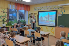 Skolotāja klases priekšā stāsta skolēniem, kuri sēž skolos