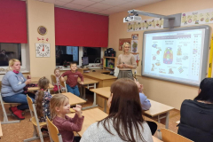 Topošie pirmklasnieki klasē kopā ar vecākiem skatās prezentāciju