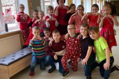 2.b klase ar klases audzinātāju ģērbušies sarkanos toņos fotogrāfējas  skolas gaiteņos