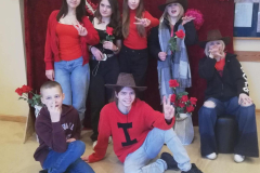 7.b klases skolēni ģērbušies sarkanos toņos, rokās tur rozes